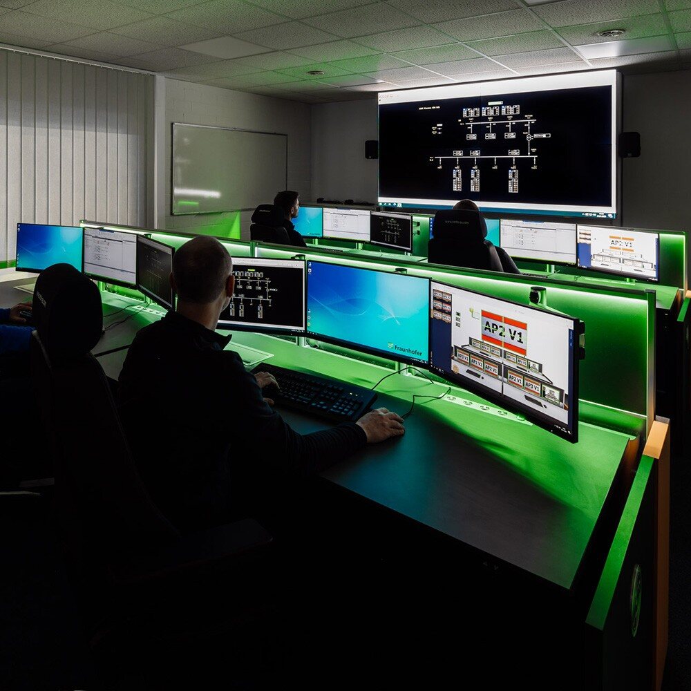 Arbeitsplätze in einer Netzleitstelle mit mehreren Monitoren und einer zentralen Netzvisualisierung.