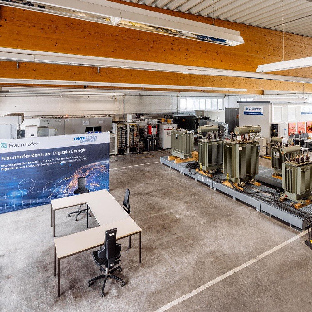 Blick in eine Versuchshalle mit Transformatoren, Prüfständen und weiteren Aufbauten für Stromnetzversuche.